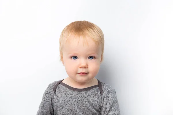 Малыш в серой рубашке смеется, глядя на камеру, изолированную на белом фоне. Концепция ухода за детьми и воспитания. — стоковое фото