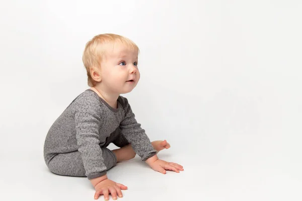 Mignon petit caucasien tout-petit bébé garçon ramper sur le plancher du studio blanc. Un petit enfant souriant portant un t-shirt jaune explore le monde. Concept de garde et d "éducation des enfants. — Photo