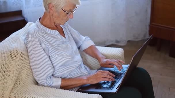 Щаслива старша жінка середнього віку на ноутбуці, що працює на комп'ютері, робить паперові роботи. літня жінка друкує на комп'ютері і купує онлайн покупки . — стокове відео