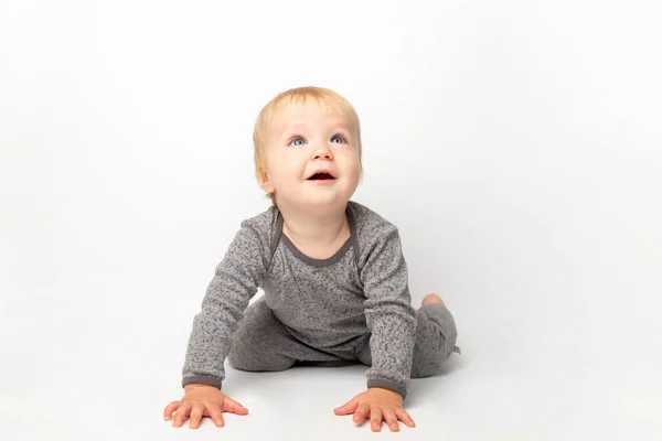 Mignon petit caucasien tout-petit bébé garçon ramper sur le plancher du studio blanc. Un petit enfant souriant portant un t-shirt jaune explore le monde. Concept de garde et d "éducation des enfants. — Photo