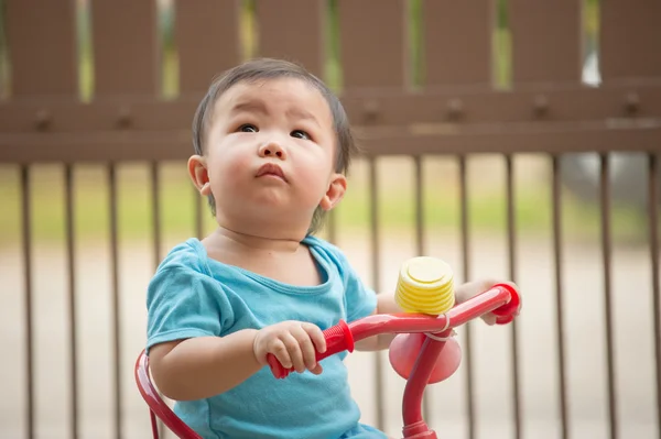 ロンパースの赤い自転車に乗って中国の 歳の男の子 ロイヤリティフリーのストック写真