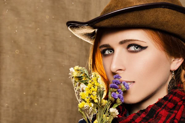 Portret pięknej młodej dziewczyny w kowbojski kapelusz z dzikie kwiaty suszone — Zdjęcie stockowe