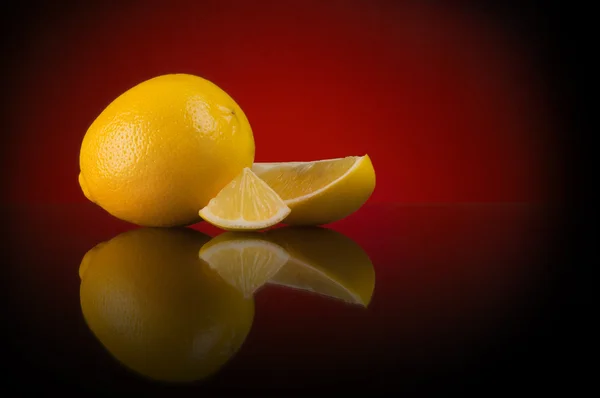 グラデーションや反射と濃い赤の背景上のレモンの配置 — ストック写真