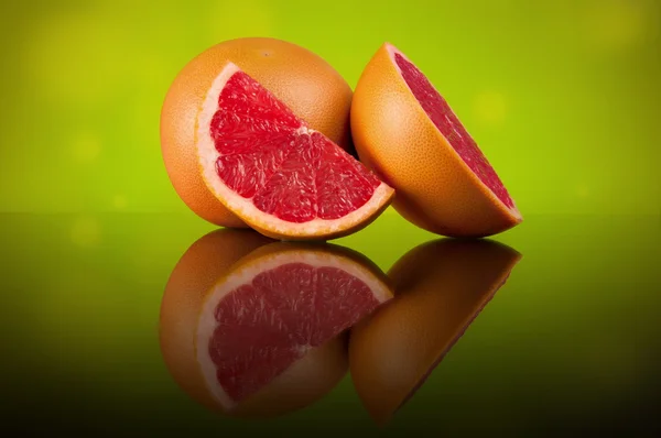 Grapefruit auf hellem abstrakten Hintergrund mit Reflexion lizenzfreie Stockfotos