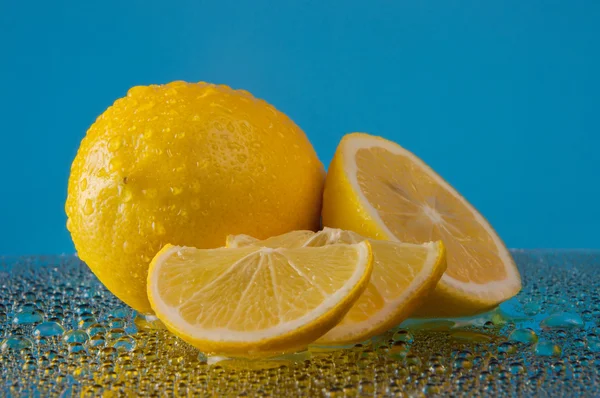 Zitronen in Wassertropfen auf blauem Hintergrund Stockbild