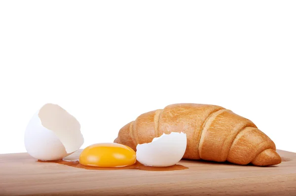 Broken raw egg on a cutting board with fresh pastries — Stock Photo, Image