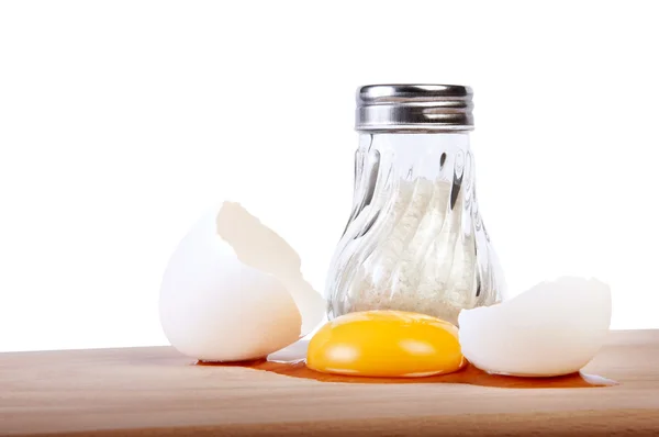 Broken raw egg on a cutting board with salt shaker — Stock Photo, Image