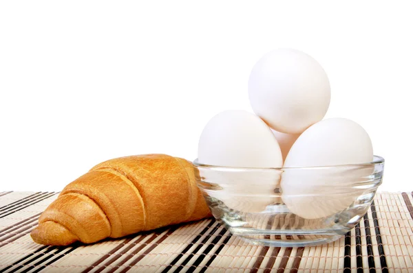 Œufs de poulet dans un vase en verre sur un tapis et un croissant — Photo