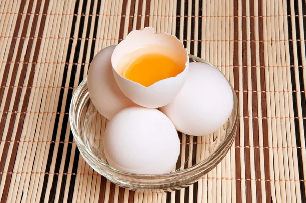 Œufs de poulet frais dans un plat en verre avec un œuf cassé — Photo