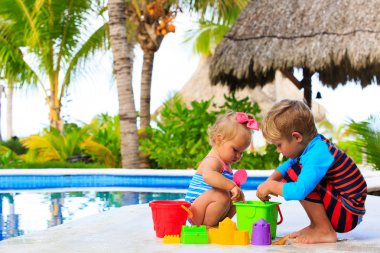 Kumsalda oynarken küçük çocuk ve yürümeye başlayan çocuk kız