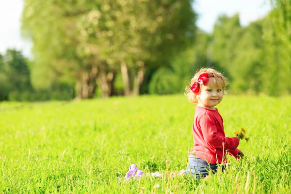 Gadis kecil yang lucu bermain dengan bunga di rumput — Stok Foto