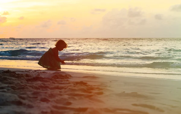 Silhuett av liten flicka leker med vattnet på stranden — Stockfoto