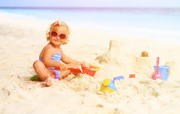 Cute little girl playing with sand on beach — Stock Photo, Image