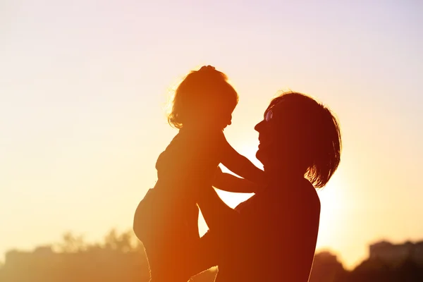 Silhouettes of father and little daughter at sunset — Stock Photo, Image