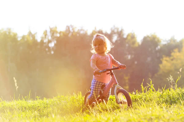 Gadis kecil naik sepeda saat matahari terbenam, anak-anak aktif — Stok Foto