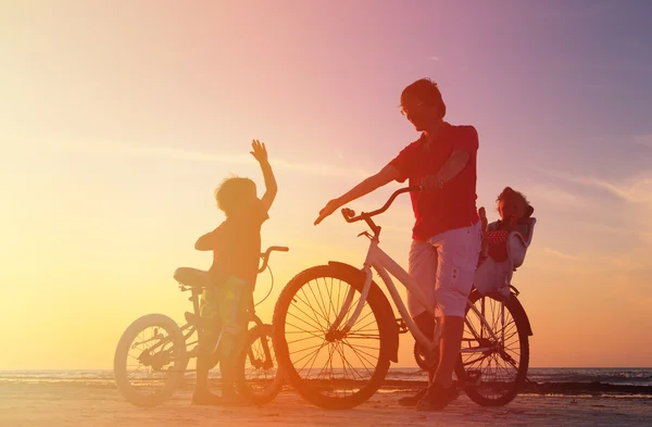 Silhouette of father with two kids on bikes — Stock Photo, Image