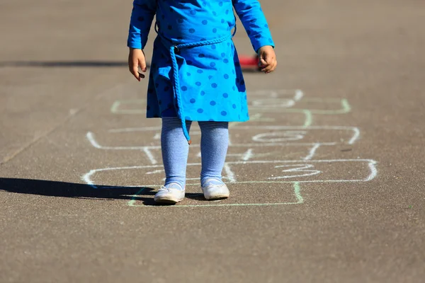 สาวน้อยเล่นฮ็อปสก็อตช์บนสนามเด็กเล่น — ภาพถ่ายสต็อก