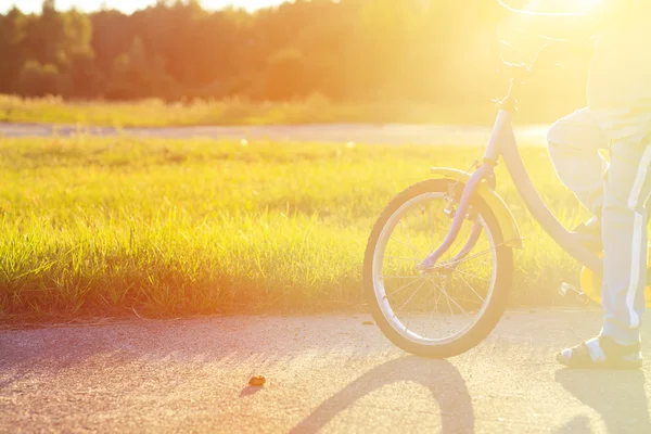 Menino pedalando bicicleta ao pôr do sol — Fotografia de Stock
