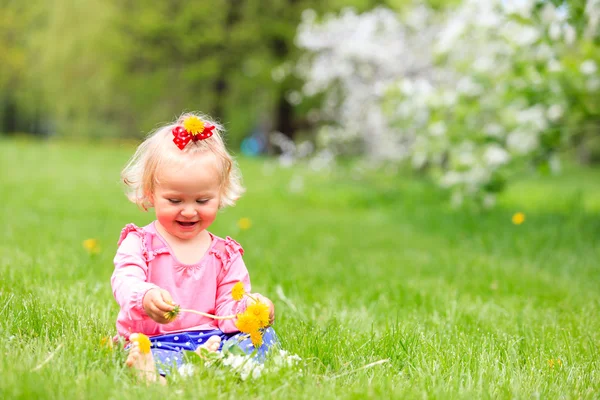 Schattig gelukkig klein meisje met bloemen in de lente — Stockfoto