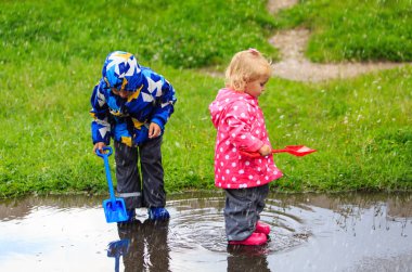 küçük erkek ve kız yağmur su ile eğleniyor