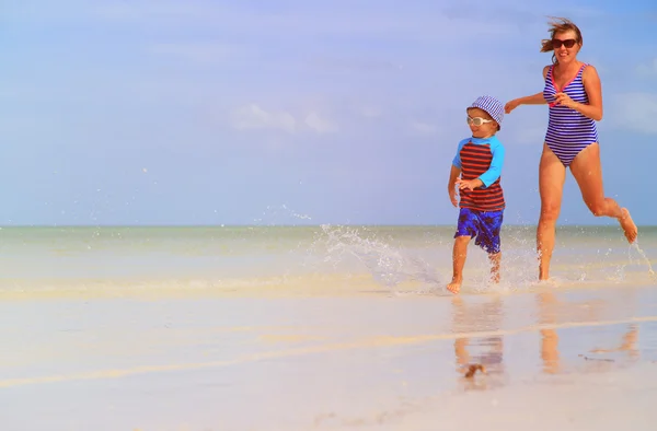 Mère et fils courant dans l'eau sur la plage — Photo