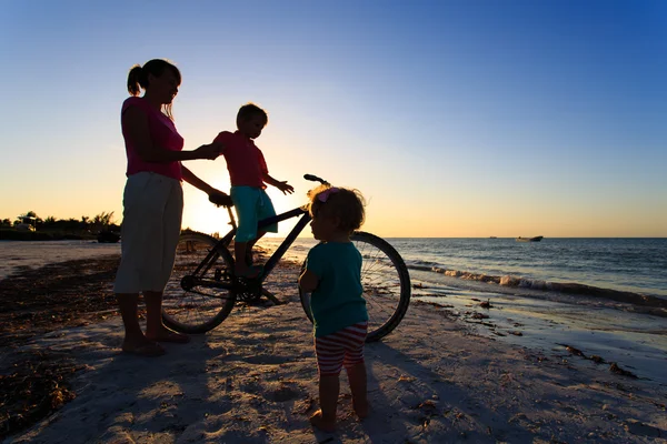 Mother with two kids biking at sunset — Stock Photo, Image