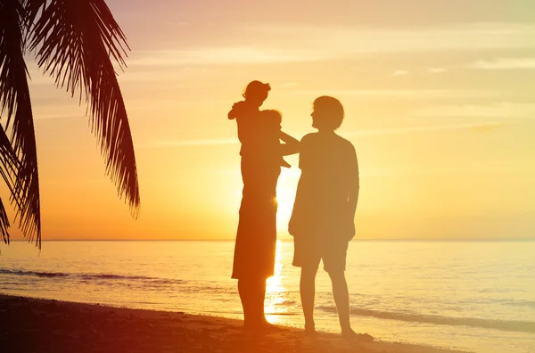 Feliz pareja con un niño pequeño en la playa del atardecer — Foto de Stock
