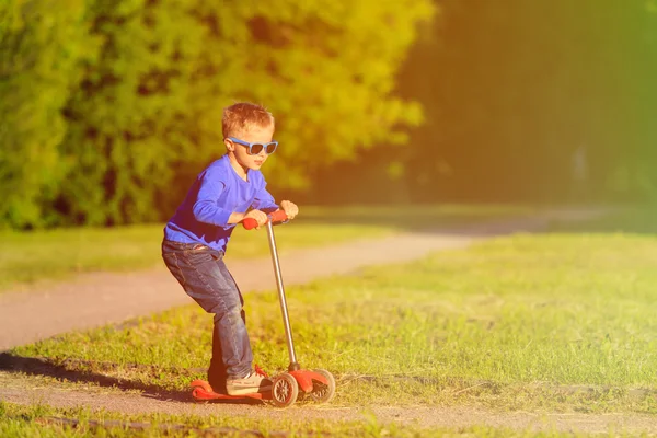Kleiner Junge fährt Roller im Sommerpark — Stockfoto