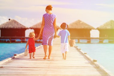 tropikal beach resort üzerinde yürüyen iki çocuklu anne
