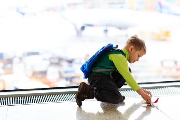 Liten pojke leker med leksak plan på flygplatsen — Stockfoto