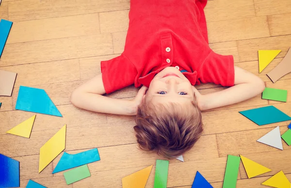 Happy little boy with puzzle toys on wooden floor — Stock Photo, Image