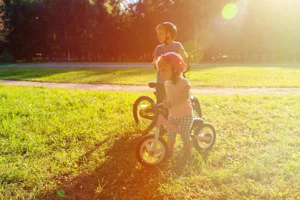 Menino e menina andando de bicicleta ao pôr do sol — Fotografia de Stock