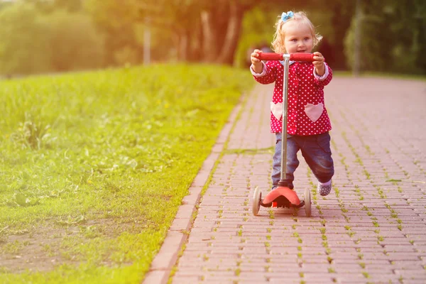 Carino bambina equitazione scooter in estate — Foto Stock