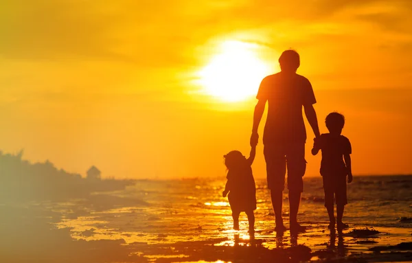 Père et deux enfants marchant au coucher du soleil — Photo