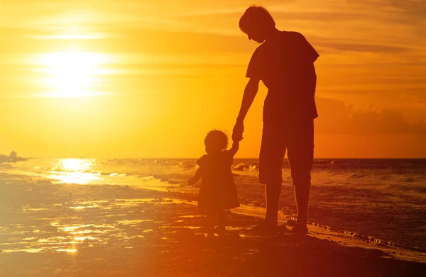 Silhuetas de pai e filha caminhando ao pôr do sol — Fotografia de Stock