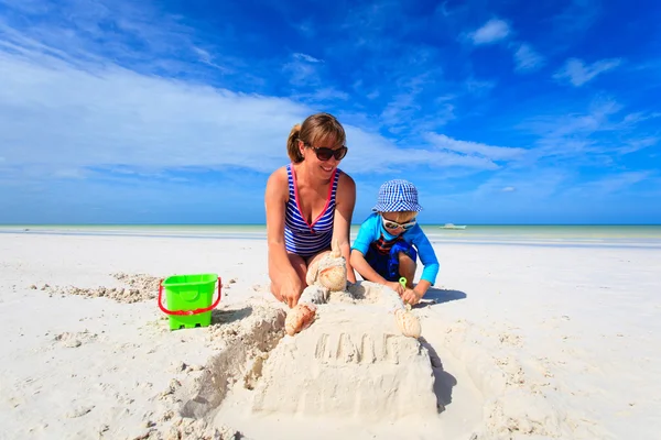 Moeder en zoon gebouw zand kasteel op strand — Stockfoto
