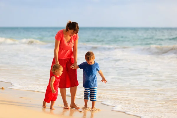 Moeder en twee kinderen wandelen op het strand — Stockfoto