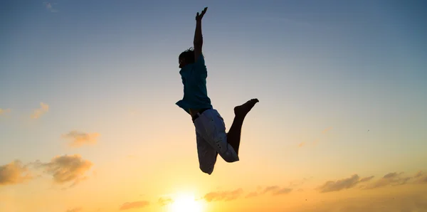 Silhueta de homem pulando no céu por do sol — Fotografia de Stock