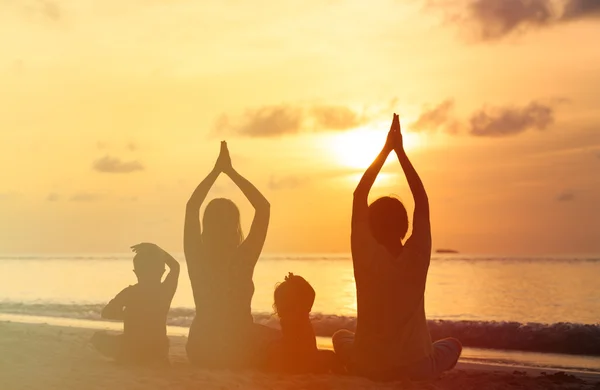 Siluet keluarga melakukan yoga di laut matahari terbenam — Stok Foto