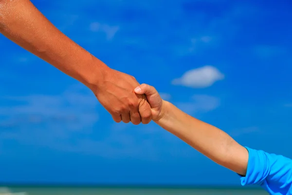 Mano di aiuto di madre e bambino su cielo alla spiaggia — Foto Stock