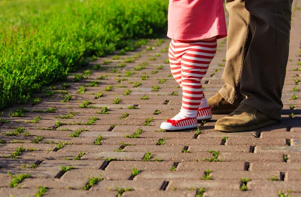 Padre ayudando a la pequeña hija a dar los primeros pasos — Foto de Stock