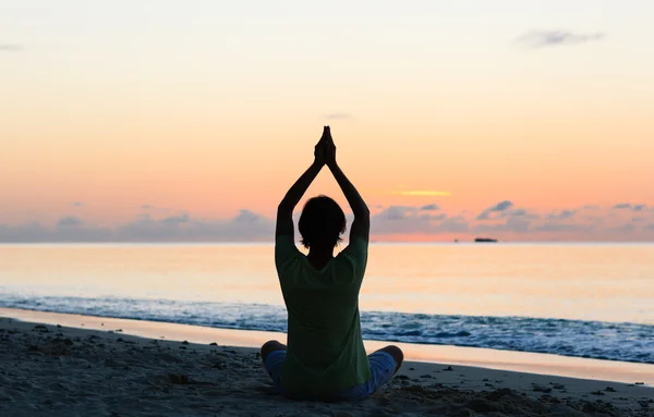 Silhouette of young man doing yoga at sunset — Stock Photo, Image