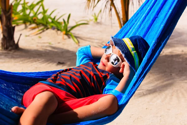 Menino feliz relaxado em rede na praia — Fotografia de Stock