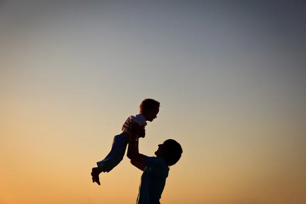 Silhouettes père et petit fils jouent au coucher du soleil — Photo