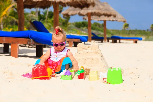 Schattig klein meisje gebouw sandcastle op strand — Stockfoto