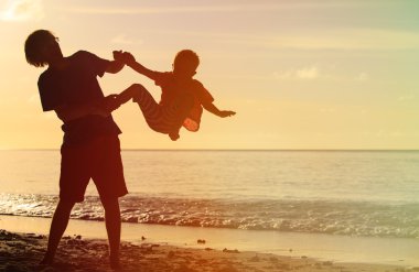 Baba ve küçük oğlu siluetleri günbatımında oynamak