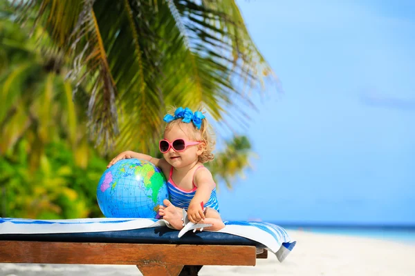 Meisje met globe en speelgoed vliegtuig op strand — Stockfoto