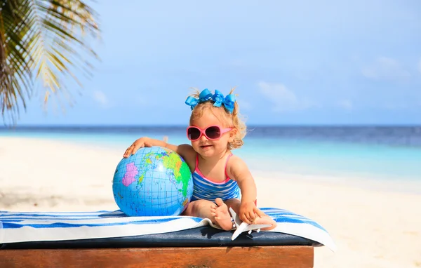 Liten flicka med globe och leksak plan på stranden — Stockfoto