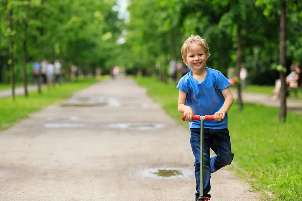 Menino feliz montando scooter no verão — Fotografia de Stock