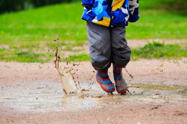 çamurlu su birikintisi içinde oynayan çocuk